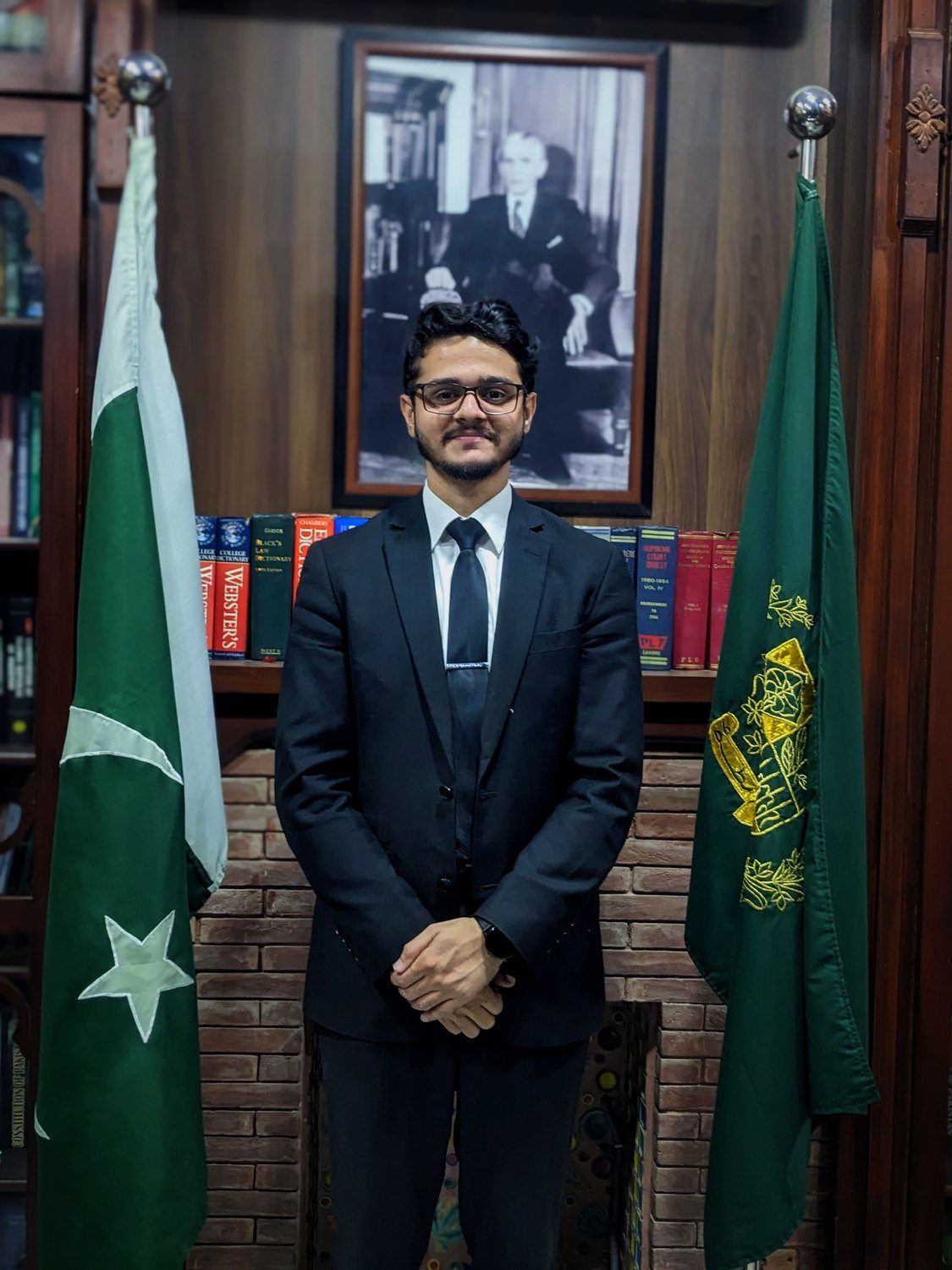 Zill E Rukh Mushtaq at chambers, between the flags of Pakistan